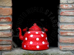 Teiera rossa a pois tra muri di mattoni